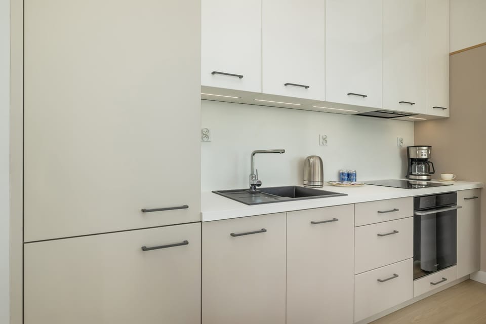 A compact kitchen with modern appliances, white cabinetry, and neutral finishes.