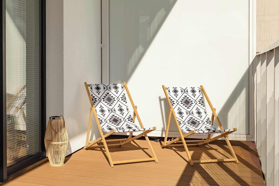 A sunny terrace area with deck chairs arranged neatly under a covered space.