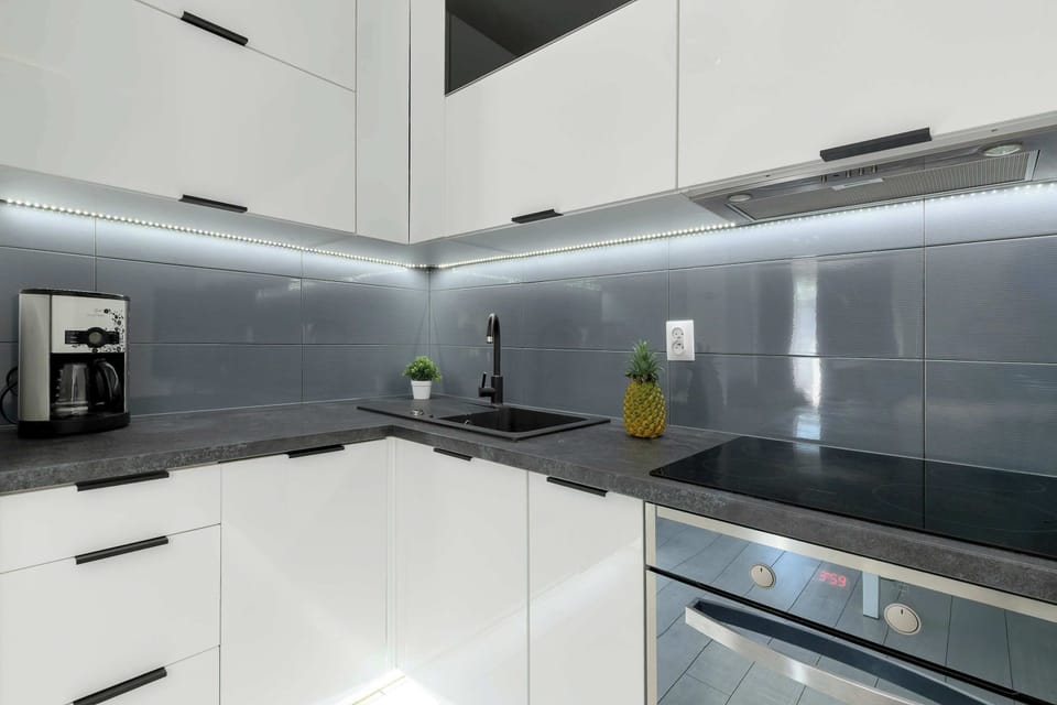 A modern kitchenette with clean white surfaces and built-in appliances, designed for compact living.

