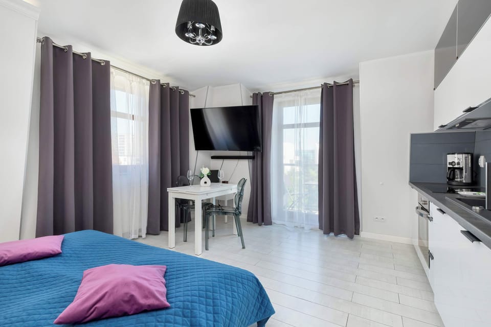 Another angle of the studio with a blue duvet, highlighting a functional workspace and large wardrobe.