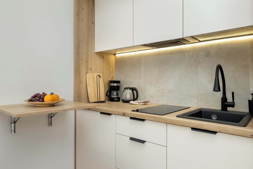 Modern kitchen with minimalist white cabinetry and wood accents – fully equipped for home-cooked meals.