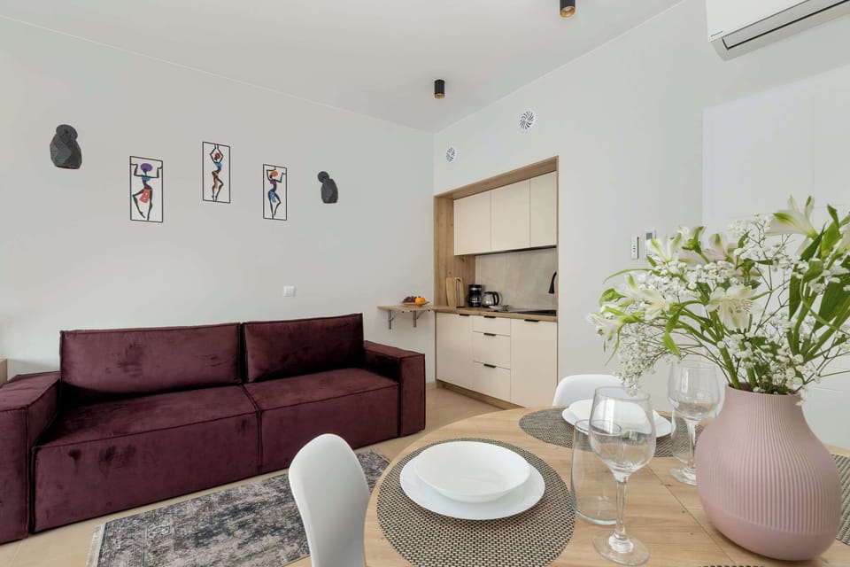 Sofa and kitchen in one frame with decorative vase on the counter – well-integrated studio layout.