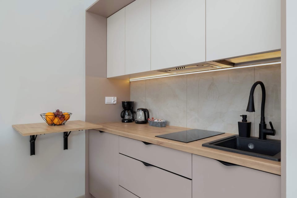 Modern kitchenette with white cabinetry, black fixtures, and essential appliances.