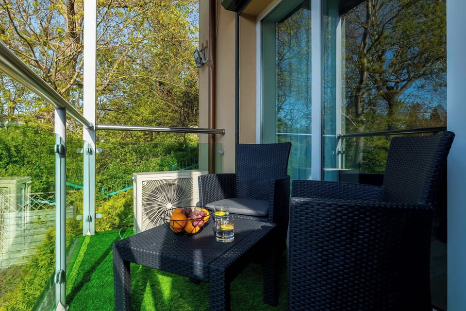 Outdoor dining area on the balcony with greenery and table set for two.