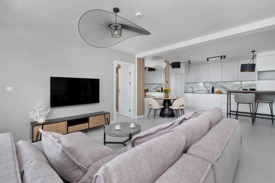 A relaxing lounge space with a sectional sofa and mounted TV. Neutral tones and soft fabrics give a calming ambiance.