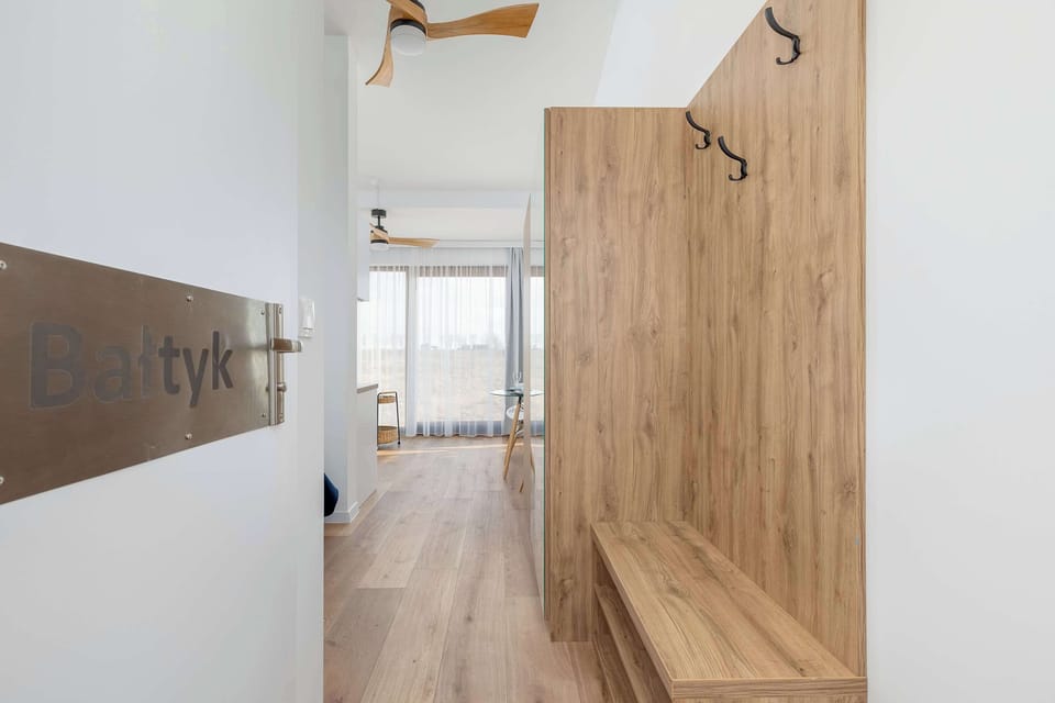 A narrow hallway with wooden flooring, white walls, and a door leading to another room.