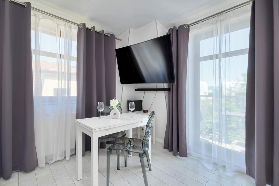 A sunny corner of the apartment with a round table and chairs set up beside a glass door leading to the balcony.

