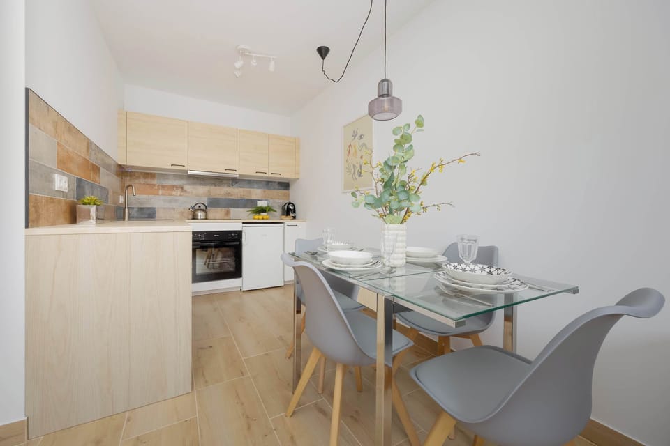 Stylish open-plan space with a dining table for four and a modern kitchenette in the background.