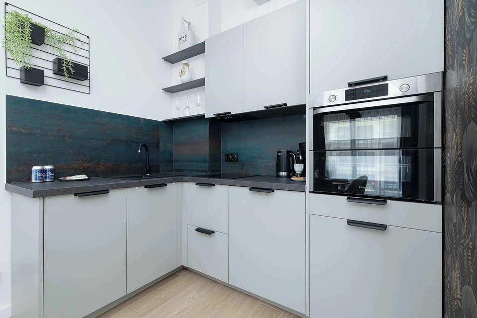 Elegant kitchen with white cabinets, contrasting black countertops and modern appliances for cooking comfort.