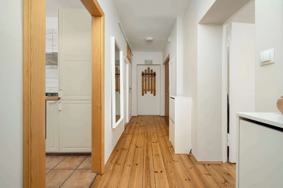 A bright hallway with wooden floors and access to various parts of the apartment. Arched doorways add architectural charm