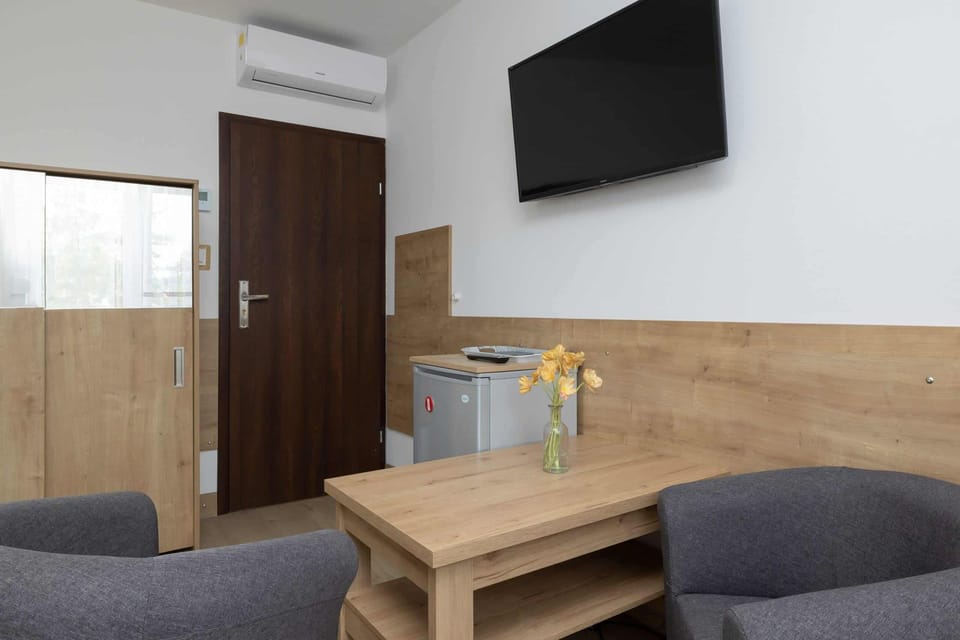 Welcoming living area with a wooden coffee table, a flat-screen television, and two armchairs.