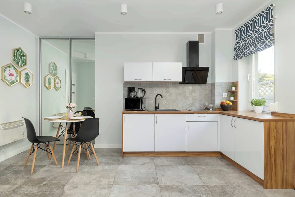 Kitchenette with white cabinets and wood additions, with coffee maker, micro-oven and induction hob.