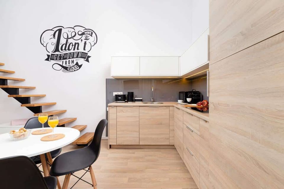 A minimalist kitchen with wooden cabinets, black countertops, and an open-plan layout.