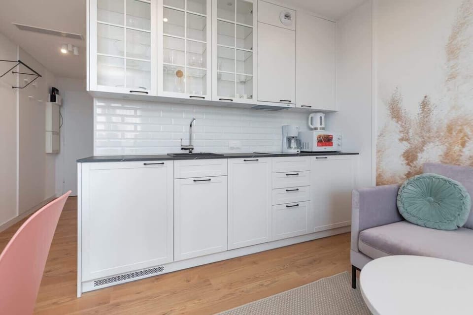 A sleek kitchen featuring white cabinets, a stove, and a microwave, with ample counter space for cooking.