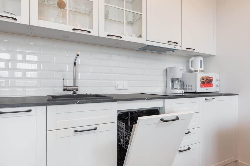 A kitchen with built-in appliances, white cabinetry, and a tiled backsplash for functionality and style.