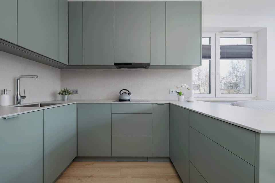 A contemporary kitchen with sleek green cabinetry and modern appliances. The layout is spacious and functional for effortless cooking.