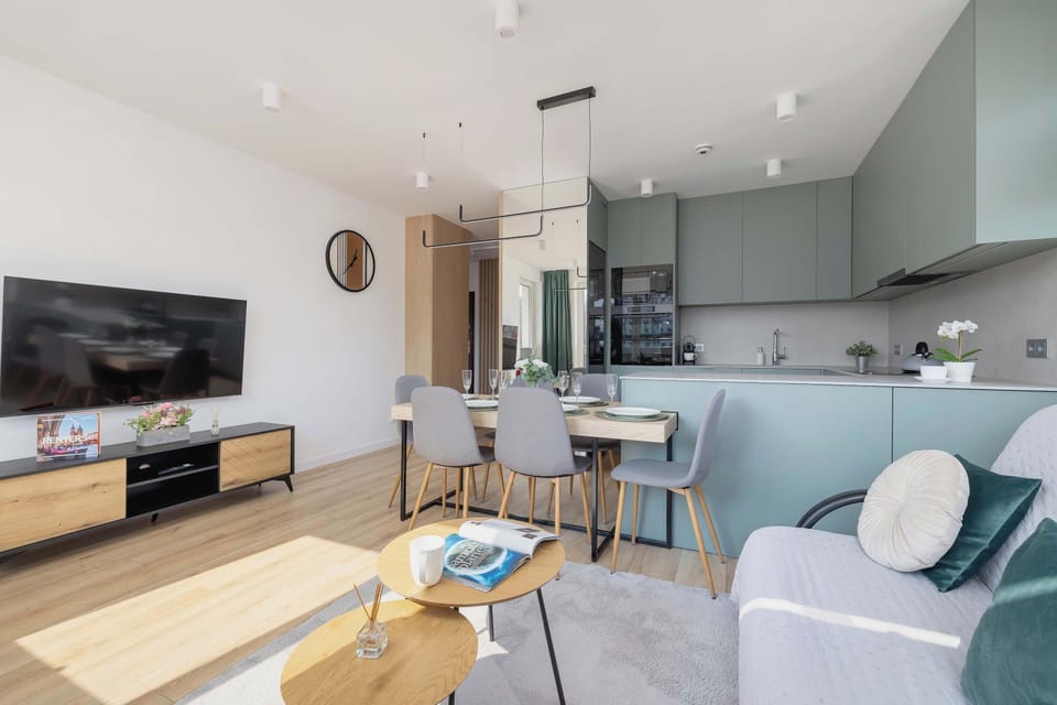 A spacious and bright living room with a cozy seating area, a TV, and modern décor. The dining table is elegantly set, making it perfect for gatherings.