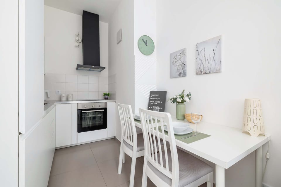 A sleek and modern kitchen with white cabinetry and a compact dining area. Equipped with a microwave, stove, and stylish countertops for convenient cooking.