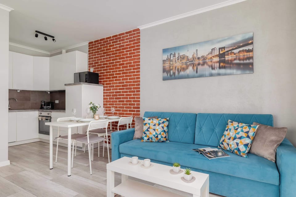 A modern living room with a blue sofa, a coffee table, and a large window. The space is bright and inviting, perfect for relaxation.