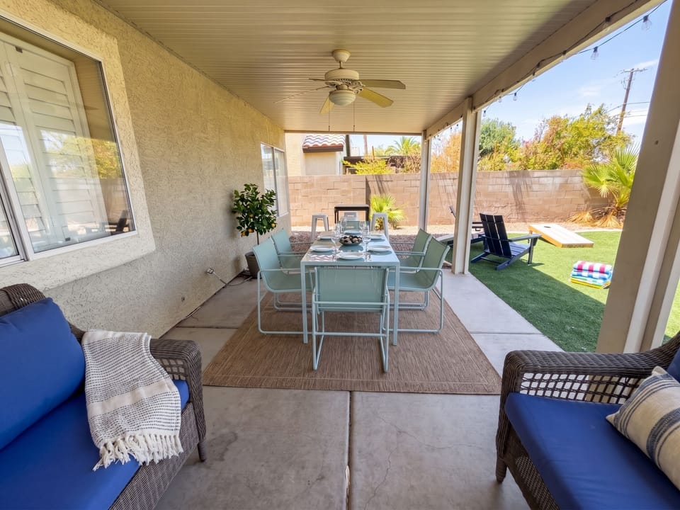 Backyard features covered patio with dining set, a bbq grill and cornhole