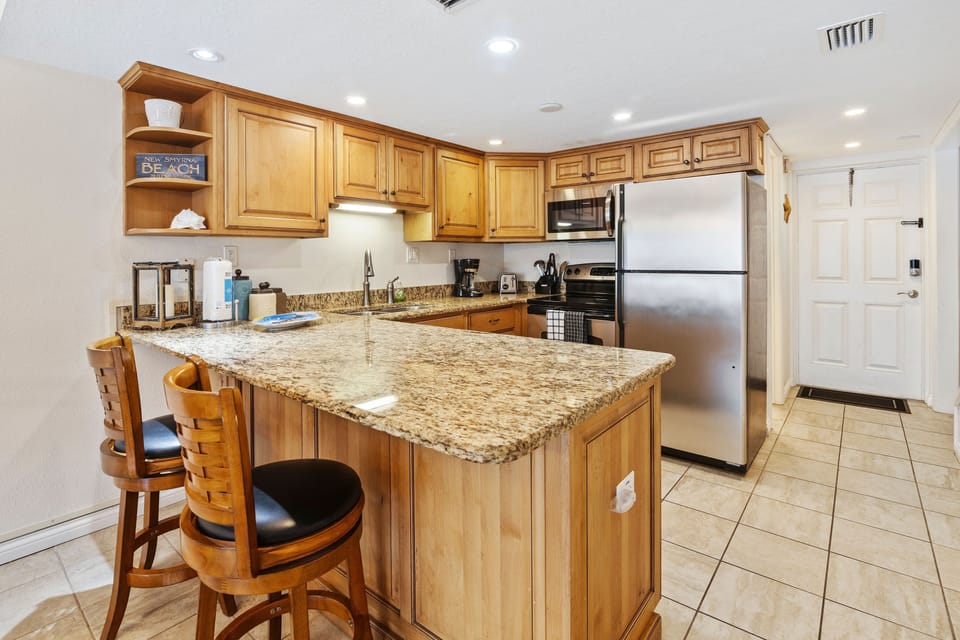 Fully equipped beachside kitchen with granite countertops, stainless steel appliances, and a breakfast bar for two. Perfect for preparing seaside meals during your stay.
