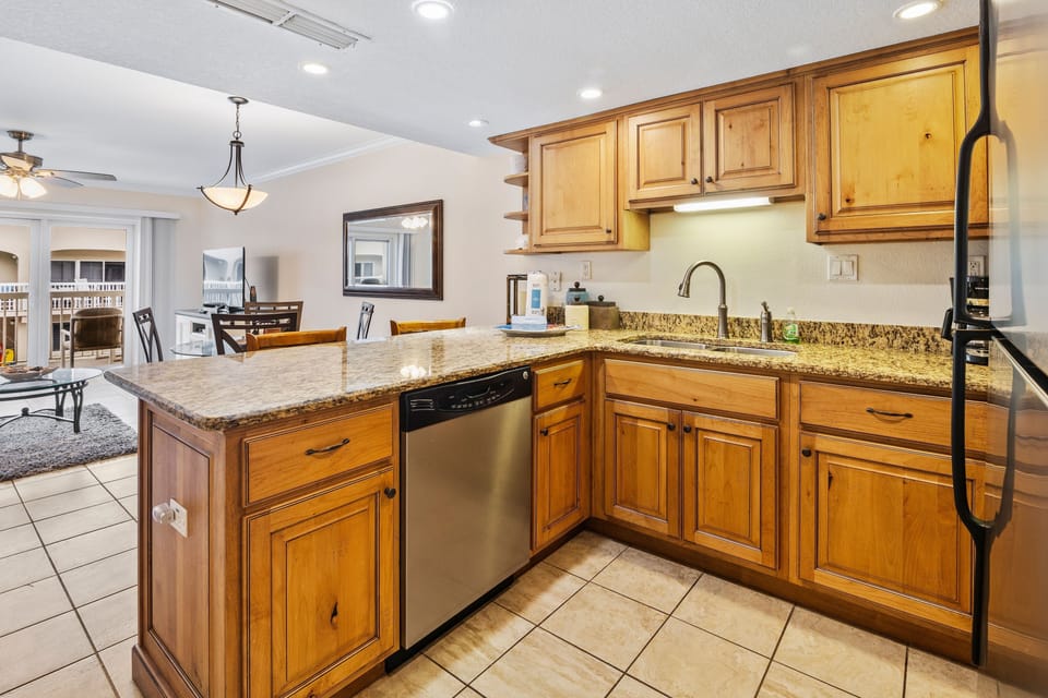 Enjoy this fully equipped coastal kitchen with granite countertops, stainless steel appliances, and bar seating. Ideal for preparing and sharing meals after a relaxing day at the beach.