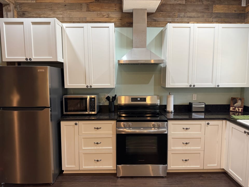 Kitchen with full-size refrigerator, stove, and four-burner cooktop.