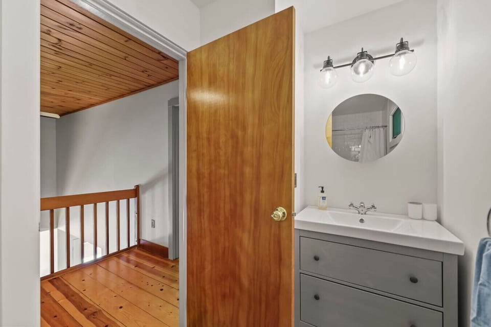 Modern bathroom with tub and shower, stylish vanity, and round mirror.