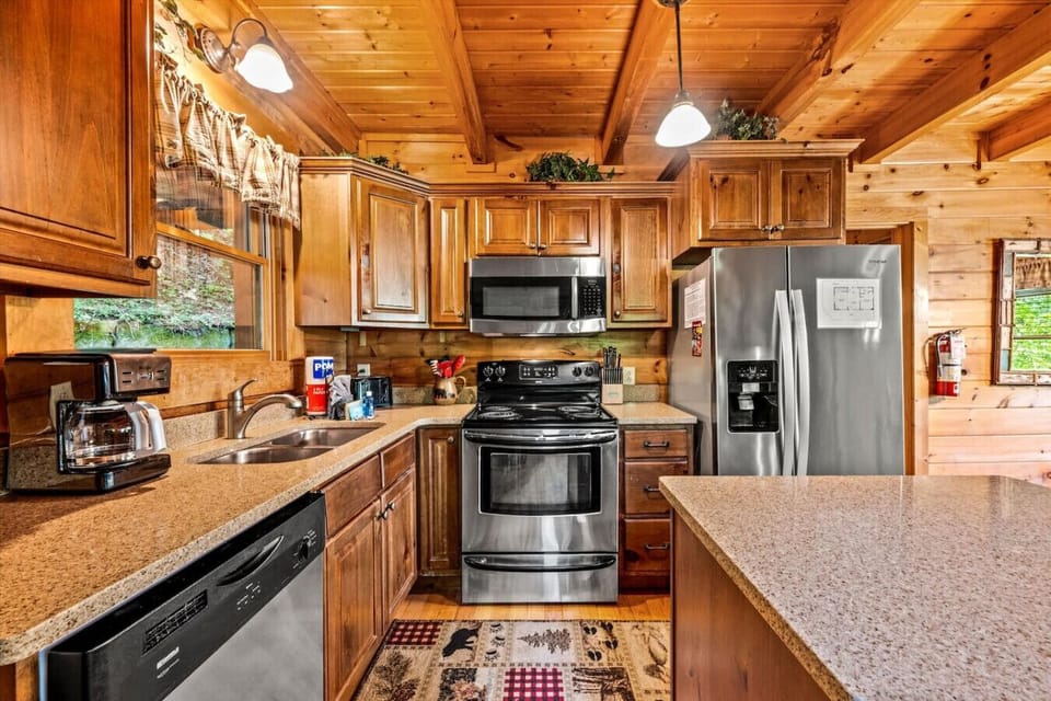 Gather in the fully equipped kitchen, complete with stainless steel appliances and rustic wood cabinetry—perfect for preparing hearty breakfasts or cozy dinners after a day in the mountains