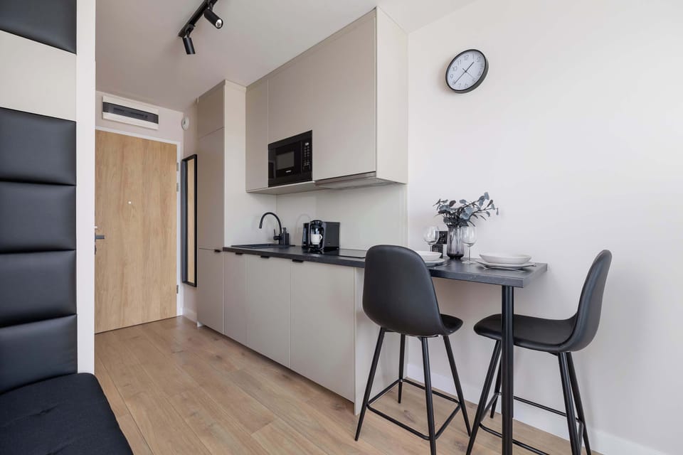 Fully equipped kitchenette with induction cooktop, refrigerator with freezer, microwave oven, electric kettle, coffee maker, washing machine and dining area.