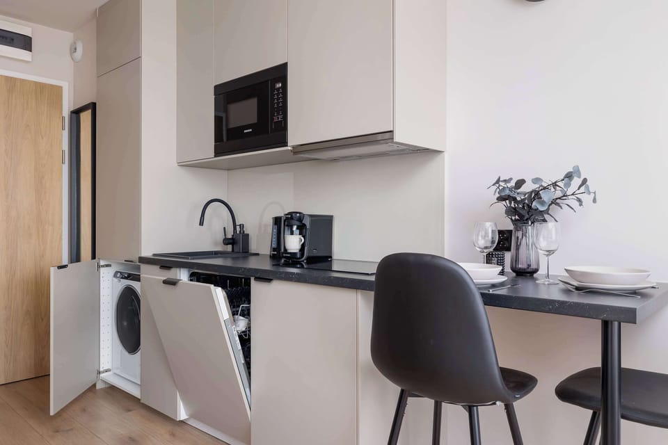 Fully equipped kitchenette with induction cooktop, refrigerator with freezer, microwave oven, electric kettle, coffee maker, washing machine and dining area.