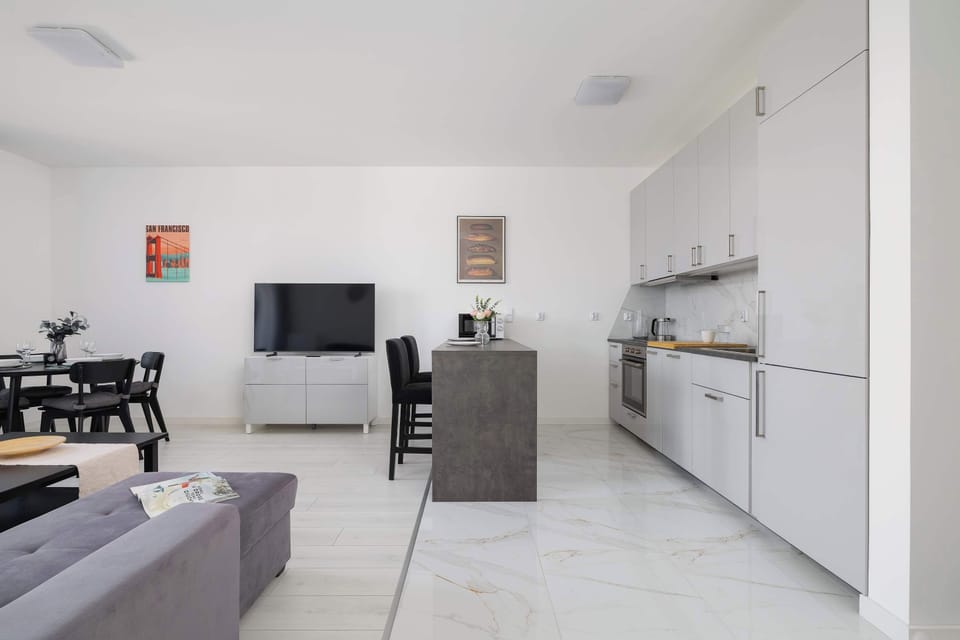 Living room with a sofa bed, TV, kitchenette and dining area.