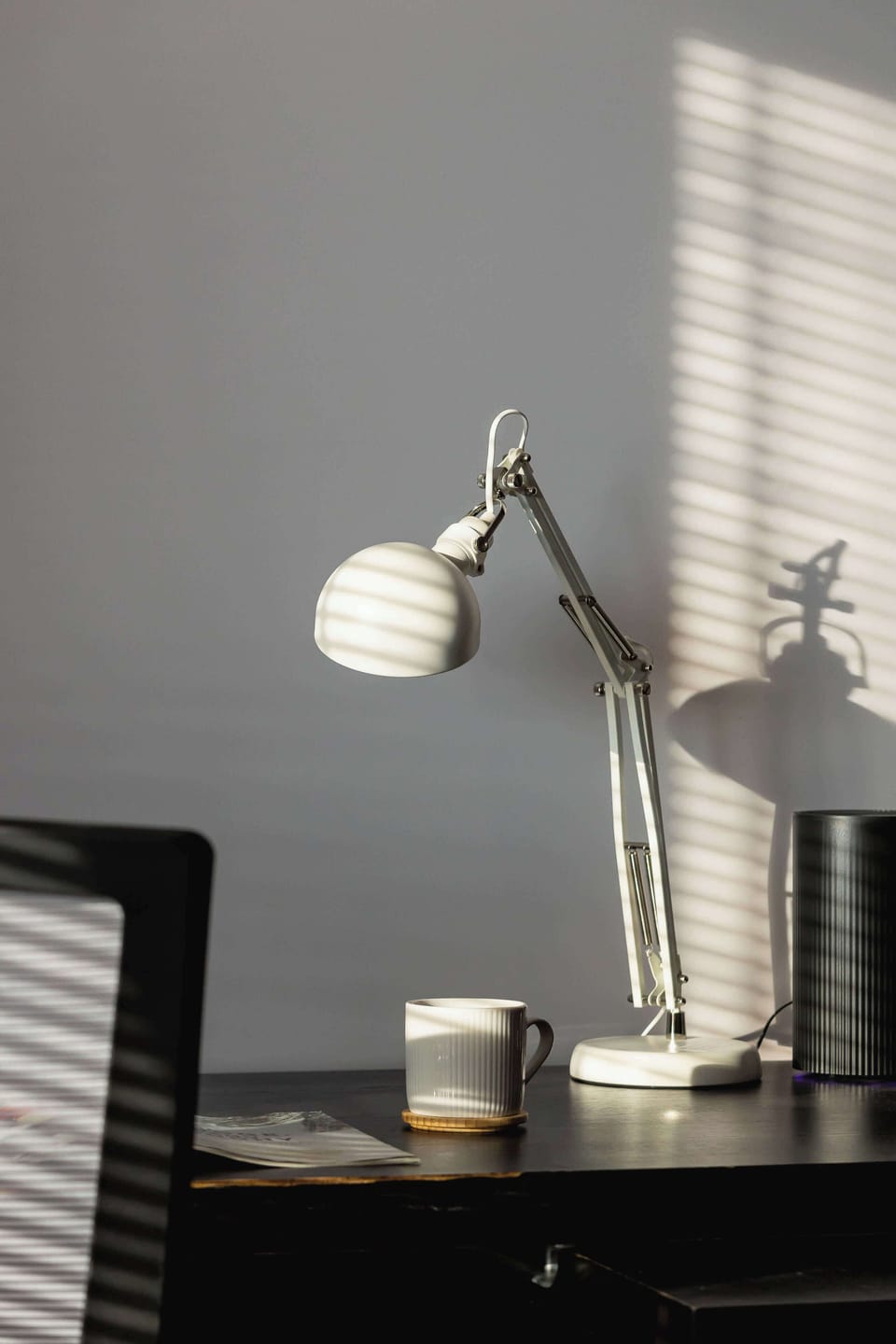 A detailed view of a stylish desk setup featuring a modern lamp and decorative elements.