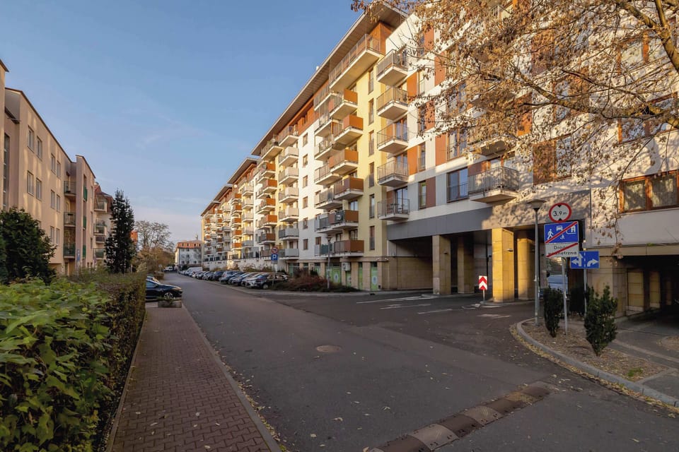 A serene street scene featuring tall trees and residential buildings, showcasing an inviting neighborhood.