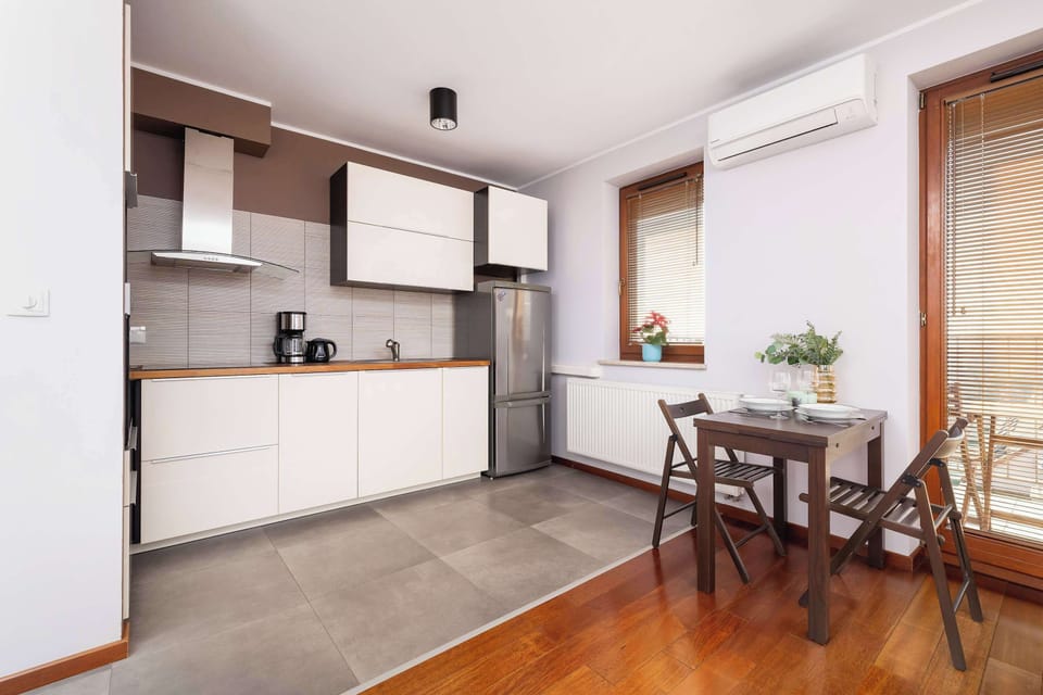 A kitchen with minimalist white cabinets, a stainless-steel refrigerator, and practical workspace.