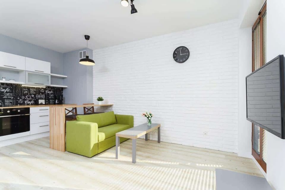 Living room with green sofa connected to kitchenette. 