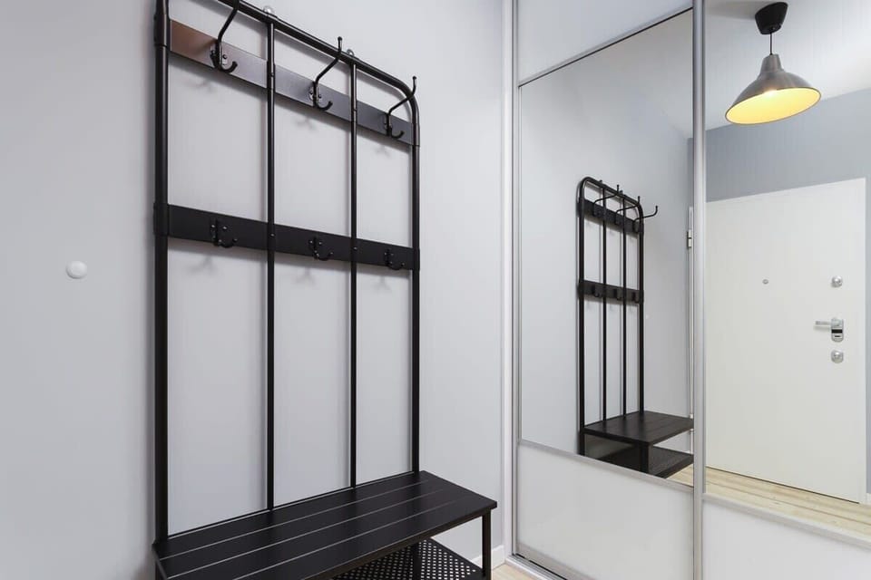 Hallway with black coat rack and shoe shelf and large wardrobe with mirrored doors. 