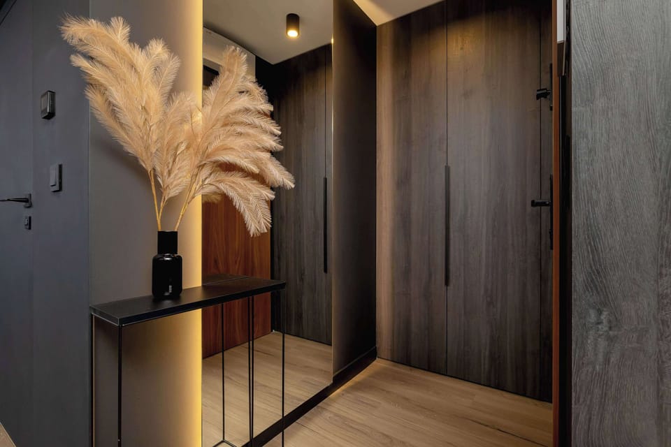 A cozy corner with decorative elements, including pampas grass in a vase, set against a wooden wall with built-in storage.

