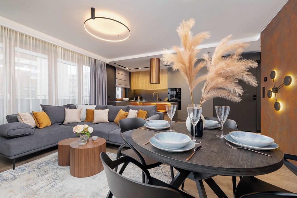Another perspective of the living and dining area, showing a more detailed view of the decor, which includes vases with pampas grass and gold accents.
