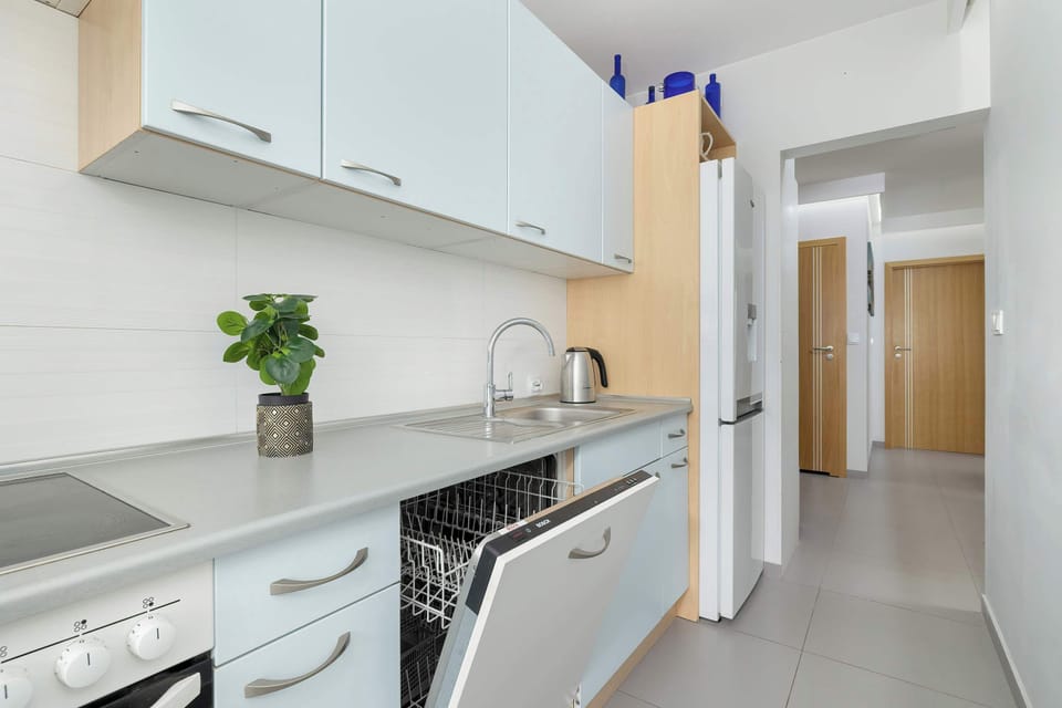 Fully equipped kitchen with electric cooktop, refrigerator with freezer, oven, microwave oven, electric kettle, dishwasher and dining area.