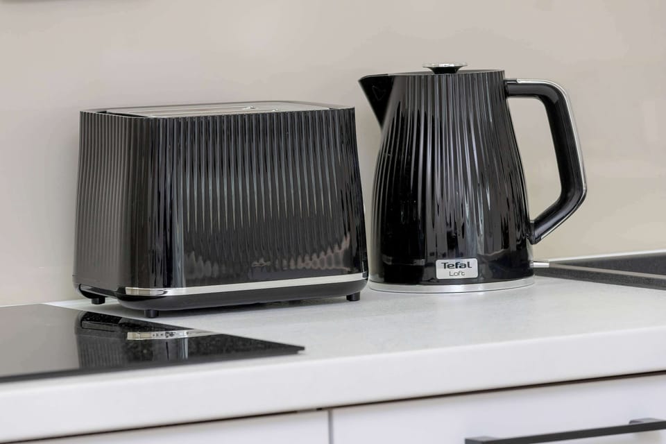 A kitchen countertop with a coffee machine, toaster, and electric kettle neatly arranged.