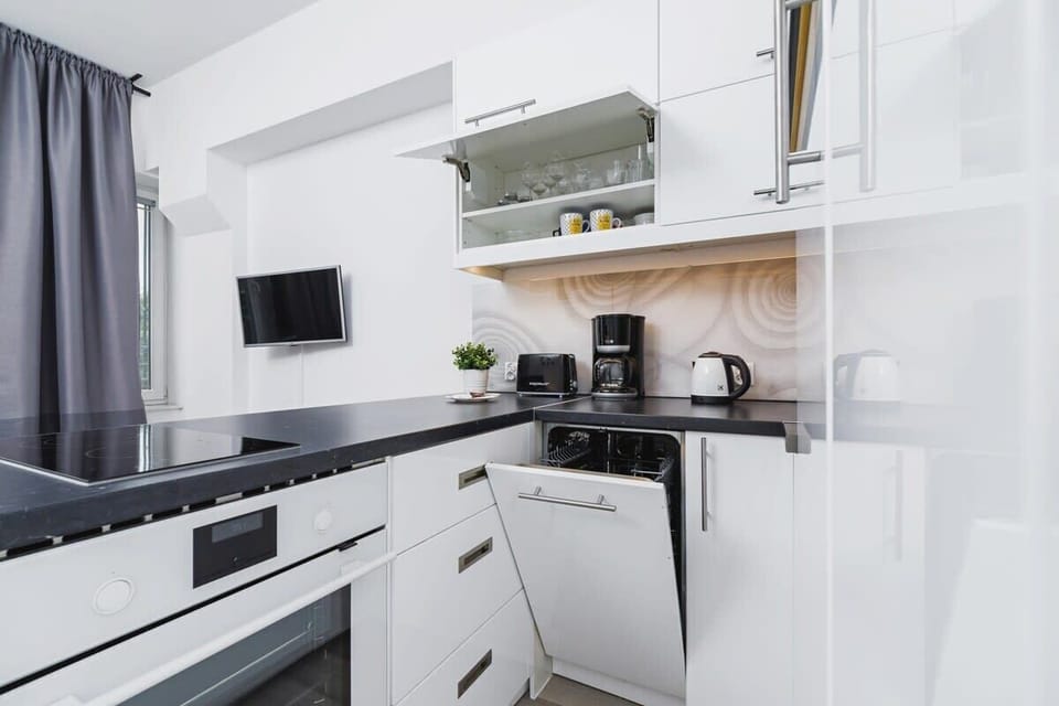 A minimalist kitchen with an oven, stove, and other appliances, complemented by white cabinetry and a sleek design.