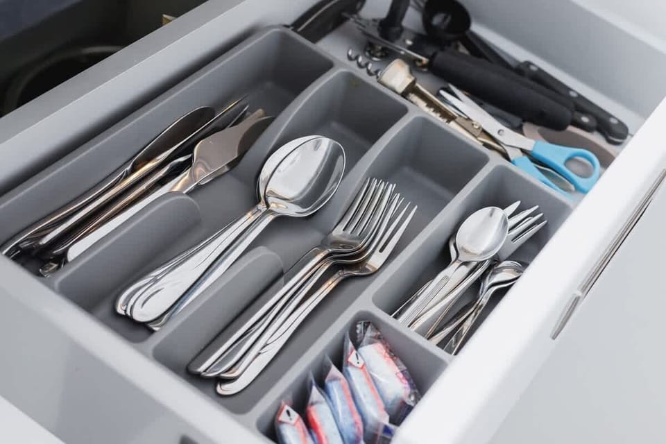 A drawer filled with neatly organized silverware, including spoons, forks, and knives.