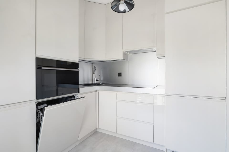 A minimalist white-toned kitchen provides a modern space for cooking.