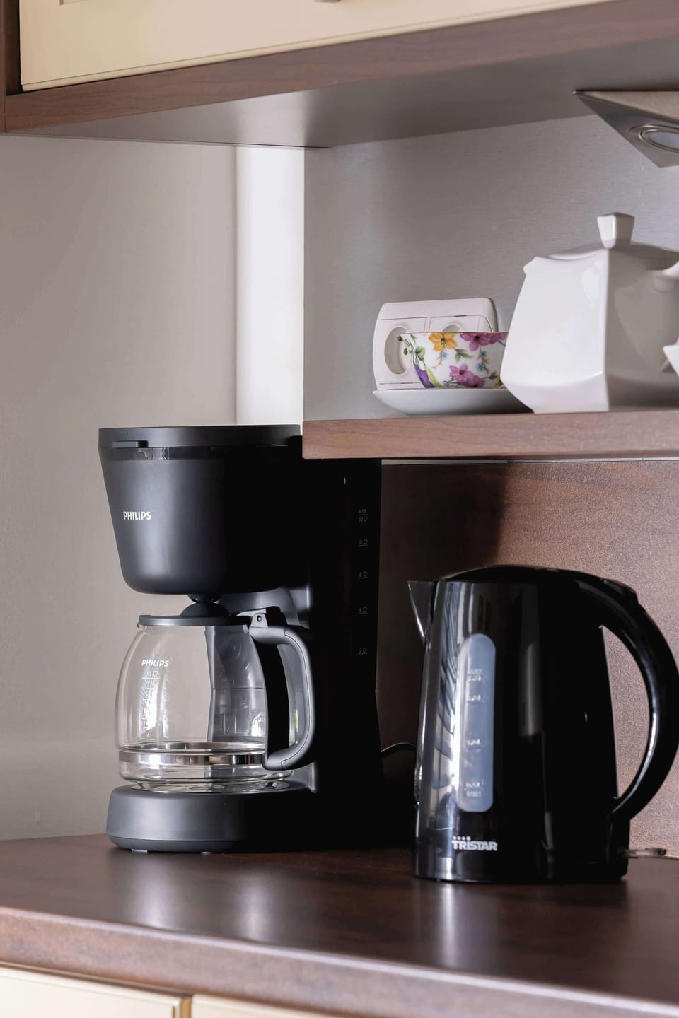 A close-up of a black coffee machine placed on a kitchen shelf for easy access.