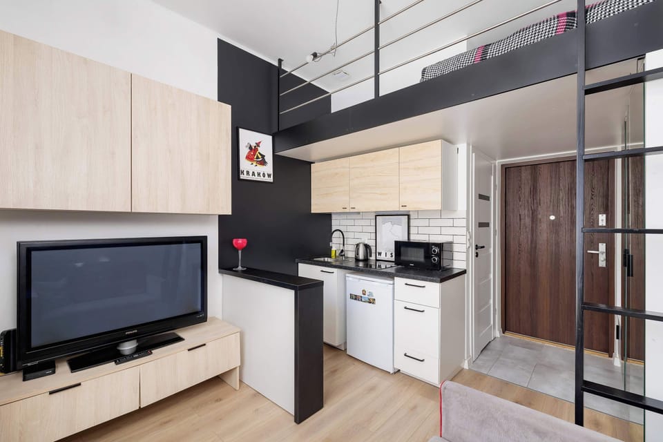 Bright and functional living space with a kitchenette and stairs leading to a mezzanine.