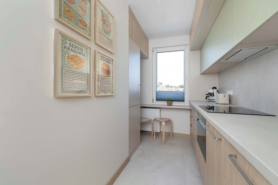 Compact and modern kitchenette with wood cabinetry and integrated appliances.