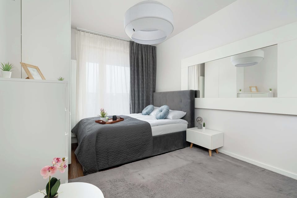 A double bed with decorative pillows, a gray headboard, and neutral tones creating a calm, modern atmosphere.