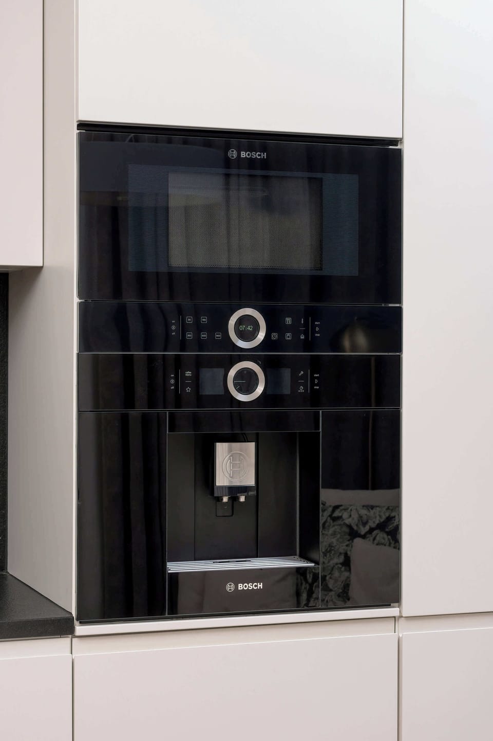 A modern kitchen showing a built-in microwave and a sleek coffee maker on the counter, combining style and function.