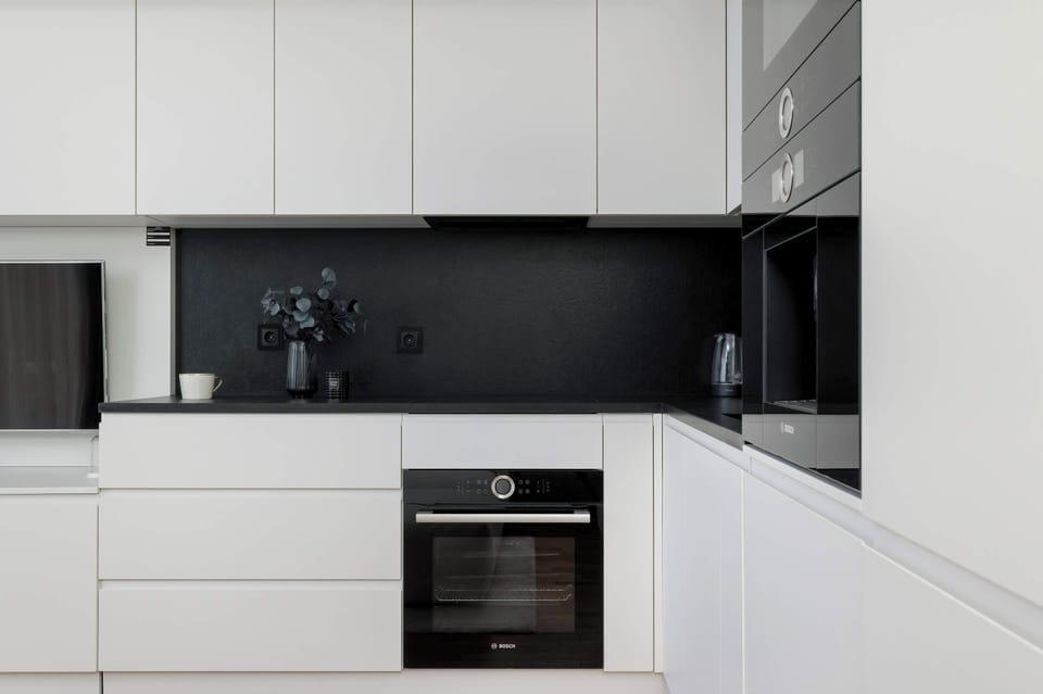  A sleek kitchen space with white cabinets, black countertops, and built-in modern appliances.